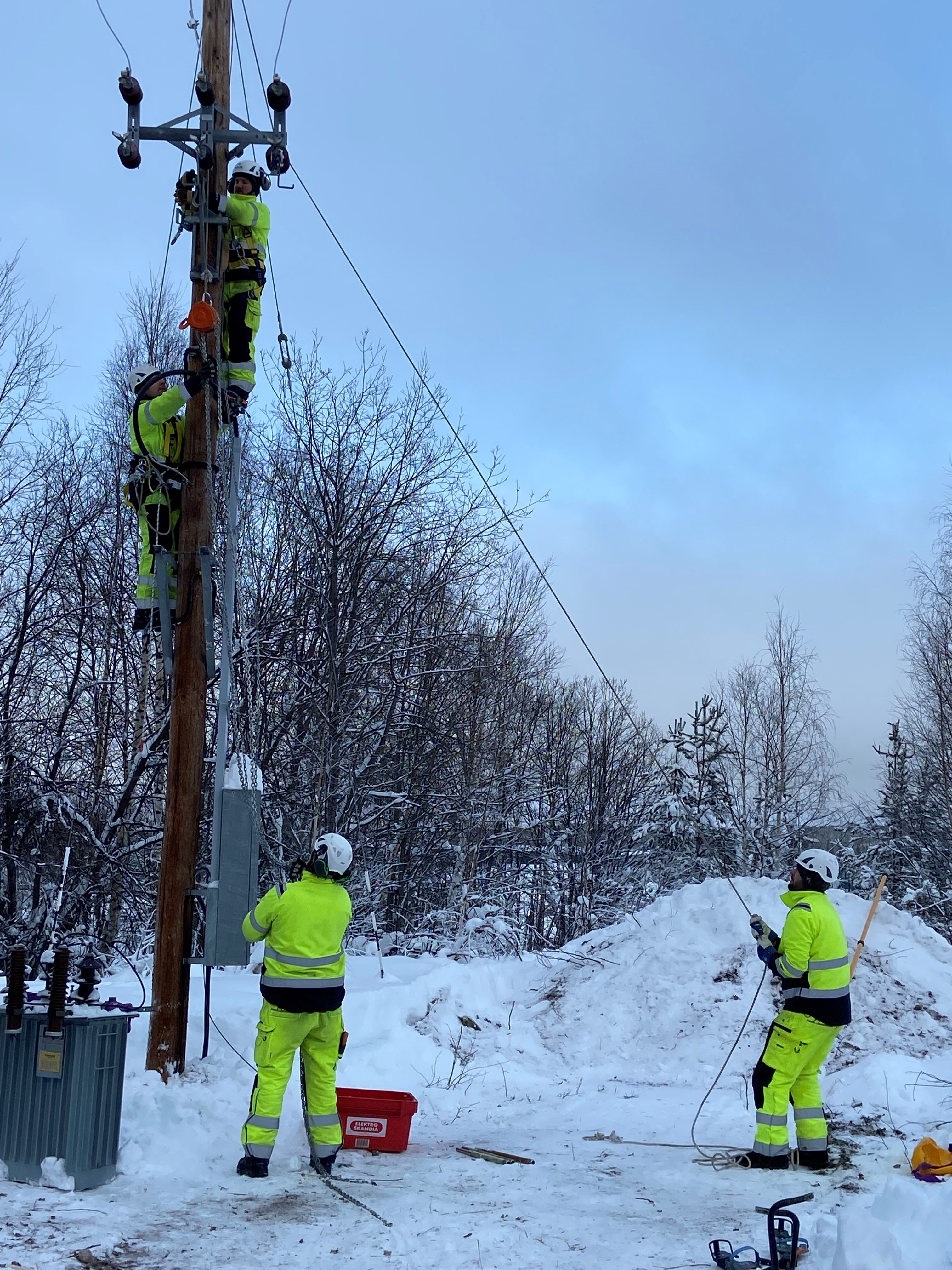 Fyra elektriker jobbar vid en elstolpe på vintern